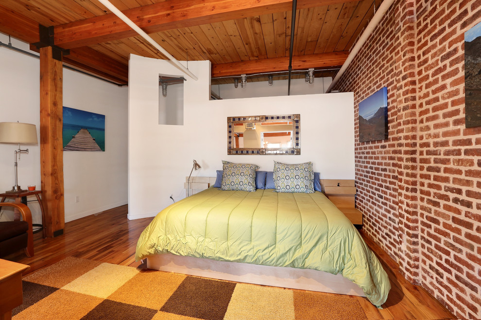 Inspiration for an industrial bedroom in Denver with white walls and medium hardwood floors.