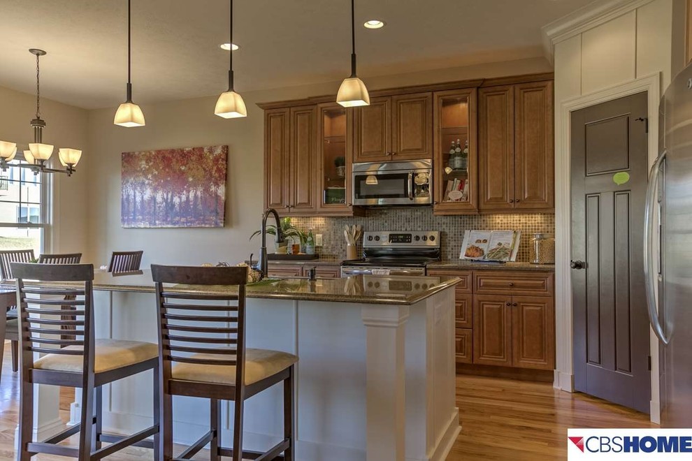 L-shaped kitchen photo in Omaha with raised-panel cabinets, medium tone wood cabinets, granite countertops and an island