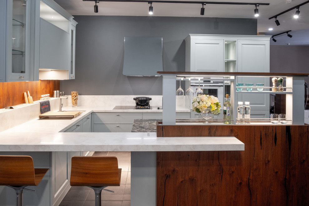 This is an example of a mid-sized transitional u-shaped kitchen in Other with grey cabinets, quartz benchtops and with island.