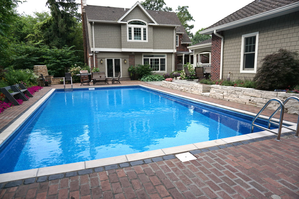 This is an example of a mid-sized traditional backyard rectangular lap pool in Other with brick pavers.