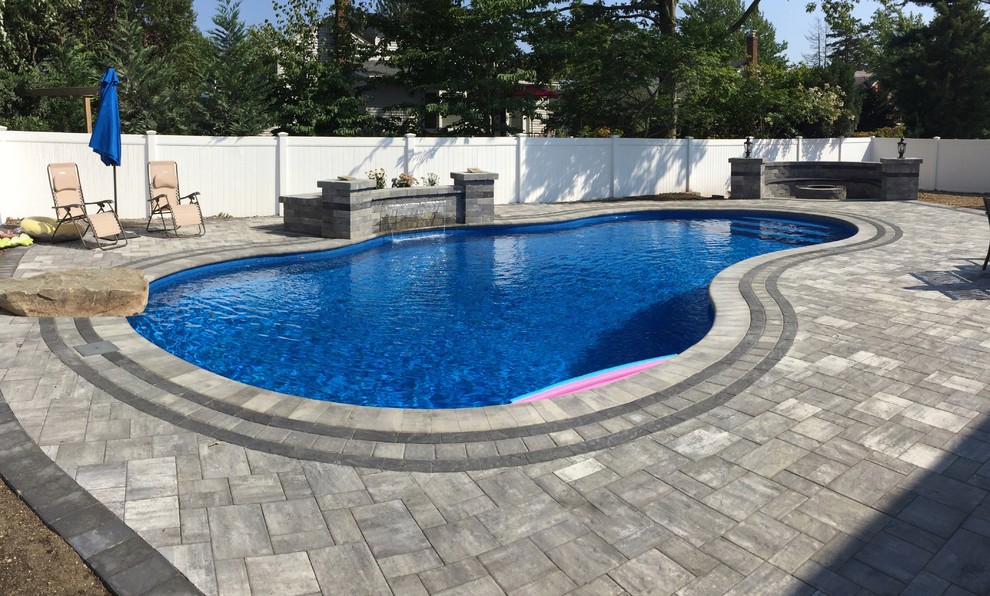 Inspiration for a large beach style backyard custom-shaped natural pool in New York with a water feature and concrete pavers.