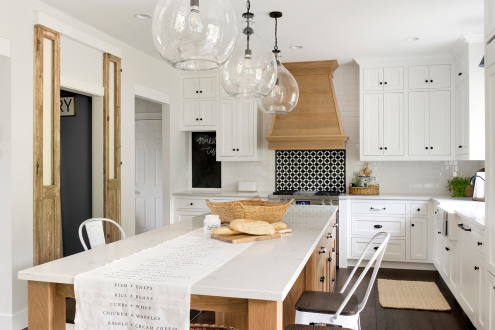 Design ideas for a large country l-shaped kitchen in Minneapolis with a farmhouse sink, white cabinets, quartzite benchtops, stainless steel appliances, dark hardwood floors, with island, brown floor, white benchtop, ceramic splashback, shaker cabinets and white splashback.