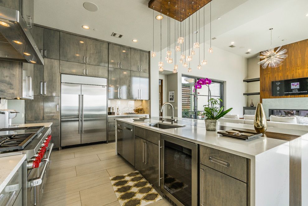 Photo of a contemporary l-shaped open plan kitchen in Austin with an undermount sink, flat-panel cabinets, grey cabinets, stainless steel appliances, with island and beige floor.