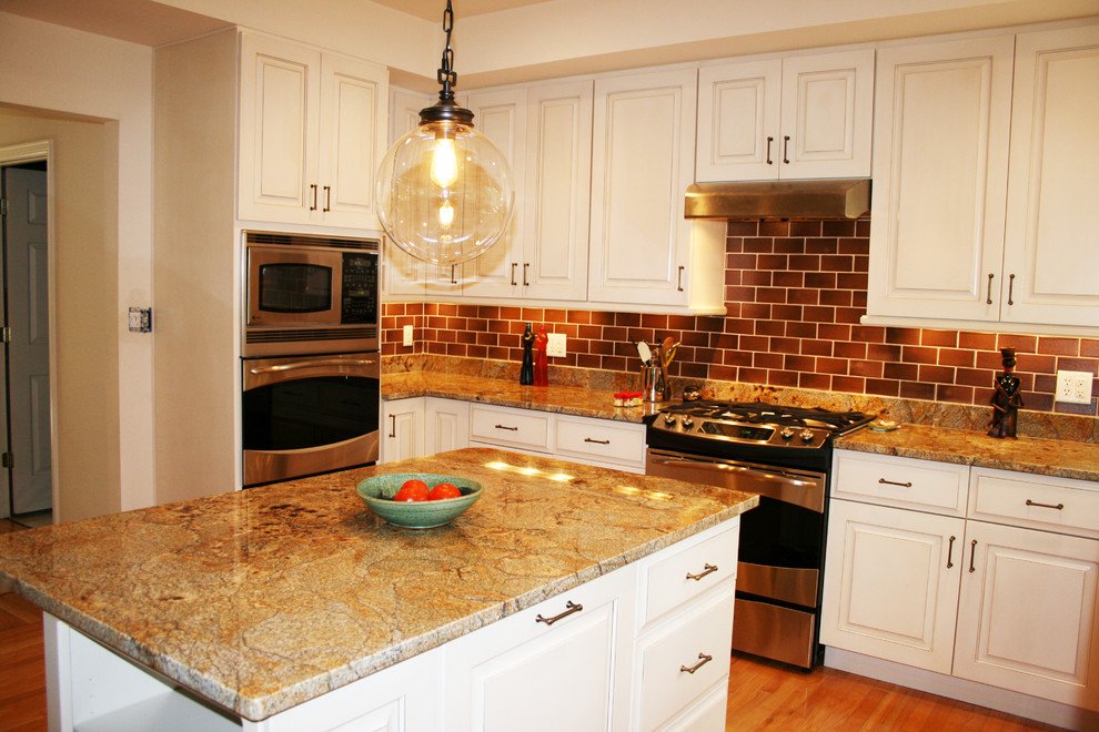Eat-in kitchen - mid-sized transitional u-shaped medium tone wood floor and brown floor eat-in kitchen idea with raised-panel cabinets, white cabinets, granite countertops, brown backsplash, subway tile backsplash, stainless steel appliances, an island and a double-bowl sink