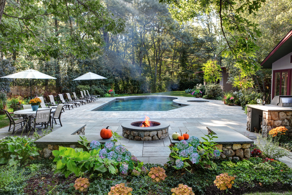 Inspiration for a large country backyard custom-shaped lap pool in Boston with natural stone pavers.