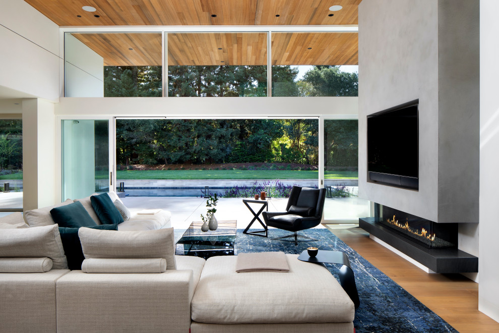 Großes, Offenes Modernes Wohnzimmer mit braunem Holzboden, Kamin, Kaminumrandung aus Beton und Multimediawand in San Francisco