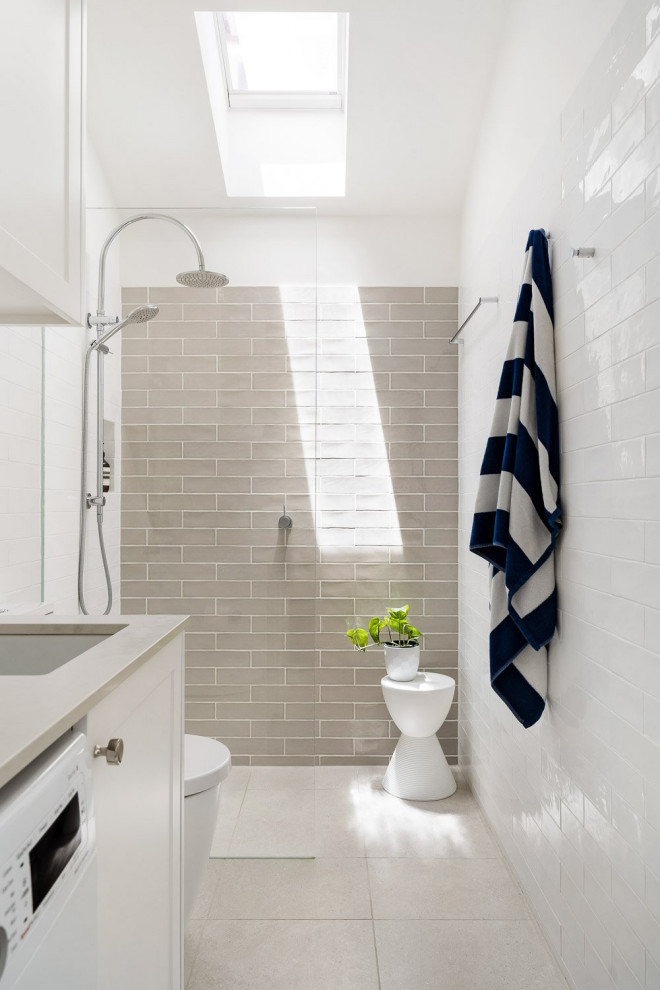 Inspiration for a mid-sized transitional master bathroom in Sydney with shaker cabinets, white cabinets, an alcove shower, a wall-mount toilet, white tile, subway tile, beige walls, cement tiles, a vessel sink, engineered quartz benchtops, beige floor, an open shower, grey benchtops, a laundry, a single vanity, a floating vanity and vaulted.