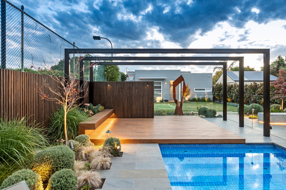 Идея дизайна: большой прямоугольный ландшафтный бассейн на заднем дворе в современном стиле с настилом
