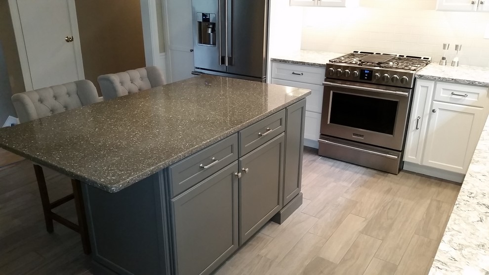 Example of a mid-sized transitional u-shaped porcelain tile and gray floor eat-in kitchen design in Boston with an undermount sink, gray cabinets, quartz countertops, stainless steel appliances, recessed-panel cabinets, white backsplash, subway tile backsplash, an island and white countertops