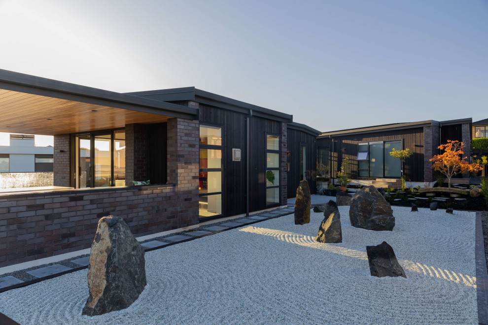 Idée de décoration pour une façade de maison noire minimaliste en brique de taille moyenne et de plain-pied avec un toit papillon, un toit en métal et un toit noir.