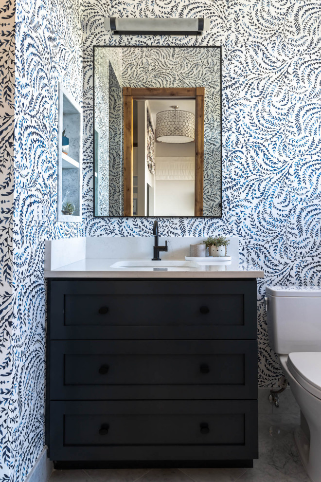 Пример оригинального дизайна: ванная комната среднего размера в стиле неоклассика (современная классика) с фасадами в стиле шейкер, синими фасадами, ванной в нише, душем в нише, белой плиткой, каменной плиткой, разноцветными стенами, мраморным полом, врезной раковиной, столешницей из искусственного кварца, белым полом, шторкой для ванной, белой столешницей, нишей, тумбой под одну раковину, встроенной тумбой, любым потолком и обоями на стенах