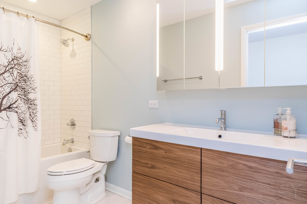 Inspiration for a small midcentury kids bathroom in Chicago with flat-panel cabinets, dark wood cabinets, an alcove tub, a shower/bathtub combo, a two-piece toilet, white tile, ceramic tile, blue walls, porcelain floors, an integrated sink, solid surface benchtops, grey floor and a shower curtain.