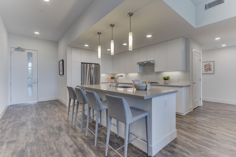 Design ideas for a l-shaped open plan kitchen in San Francisco with an undermount sink, flat-panel cabinets, white cabinets, stainless steel appliances, with island and white benchtop.