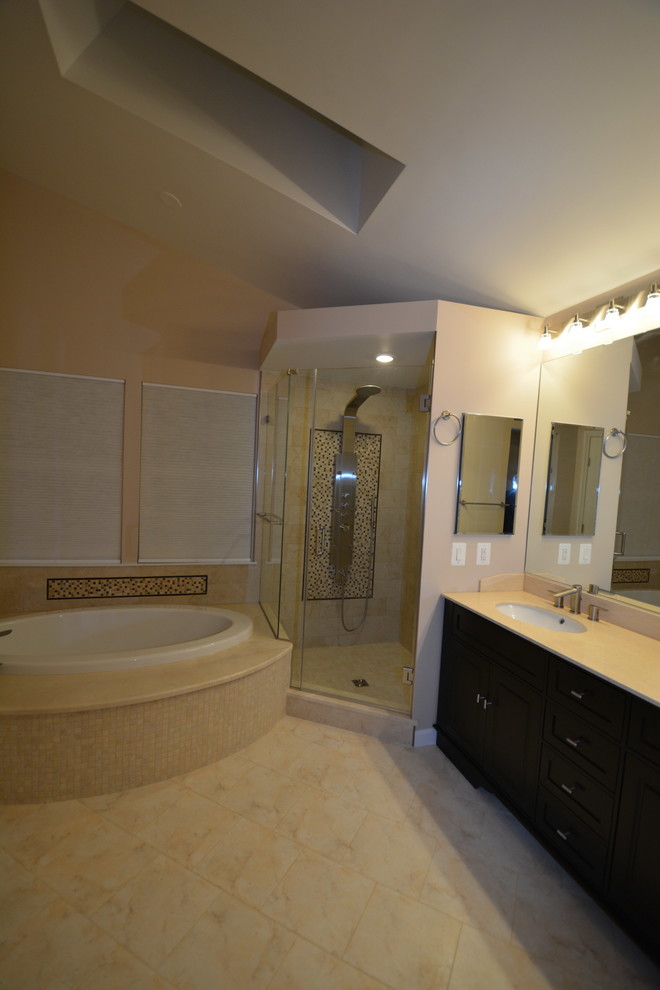 Large transitional master beige tile and stone tile marble floor and beige floor drop-in bathtub photo in Baltimore with dark wood cabinets, beige walls, an undermount sink, a two-piece toilet, beaded inset cabinets, solid surface countertops, a hinged shower door and beige countertops