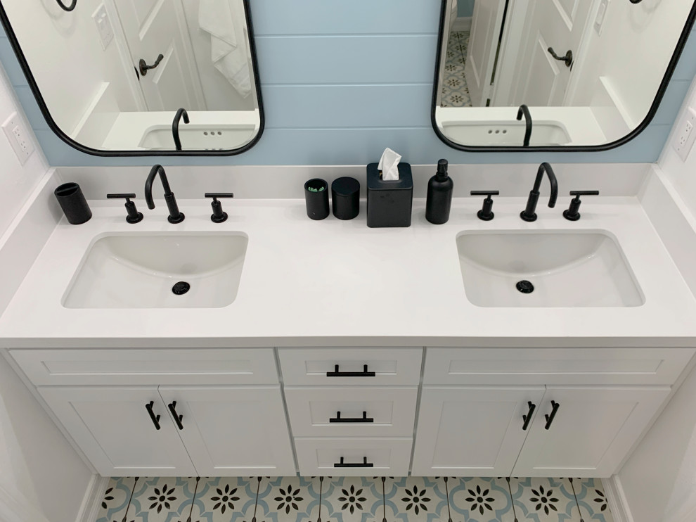 This is an example of a small contemporary family bathroom in Orange County with shaker cabinets, white cabinets, a built-in bath, a shower/bath combination, a one-piece toilet, white tiles, ceramic tiles, blue walls, ceramic flooring, a submerged sink, engineered stone worktops, multi-coloured floors, a sliding door, white worktops, a feature wall, double sinks, a built in vanity unit and tongue and groove walls.