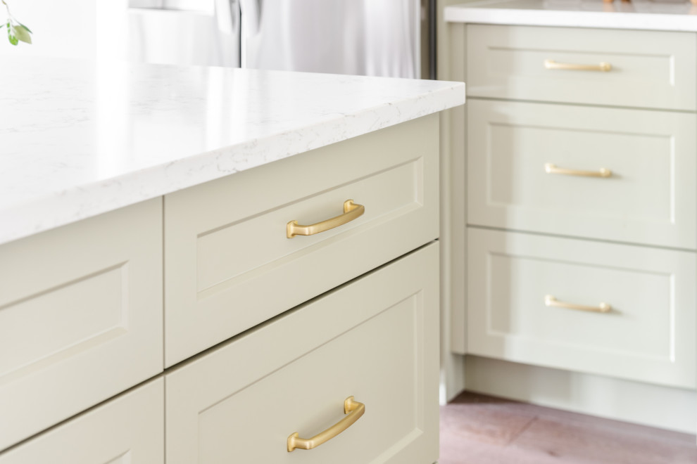 Example of a small transitional brown floor kitchen design with shaker cabinets, green cabinets, white backsplash, stainless steel appliances, an island and white countertops