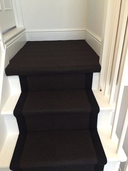 Photo of a mid-sized contemporary carpeted u-shaped staircase in London with wood railing.