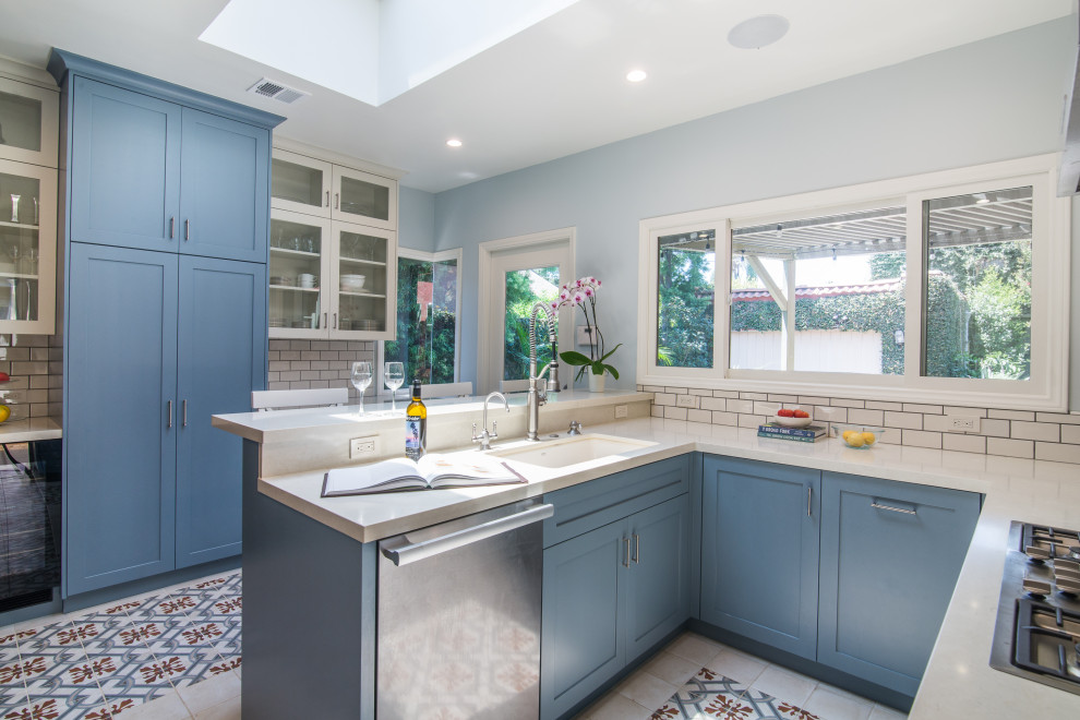 Inspiration for a mid-sized transitional u-shaped separate kitchen with an undermount sink, shaker cabinets, blue cabinets, limestone benchtops, white splashback, subway tile splashback, stainless steel appliances, ceramic floors, a peninsula, multi-coloured floor and white benchtop.