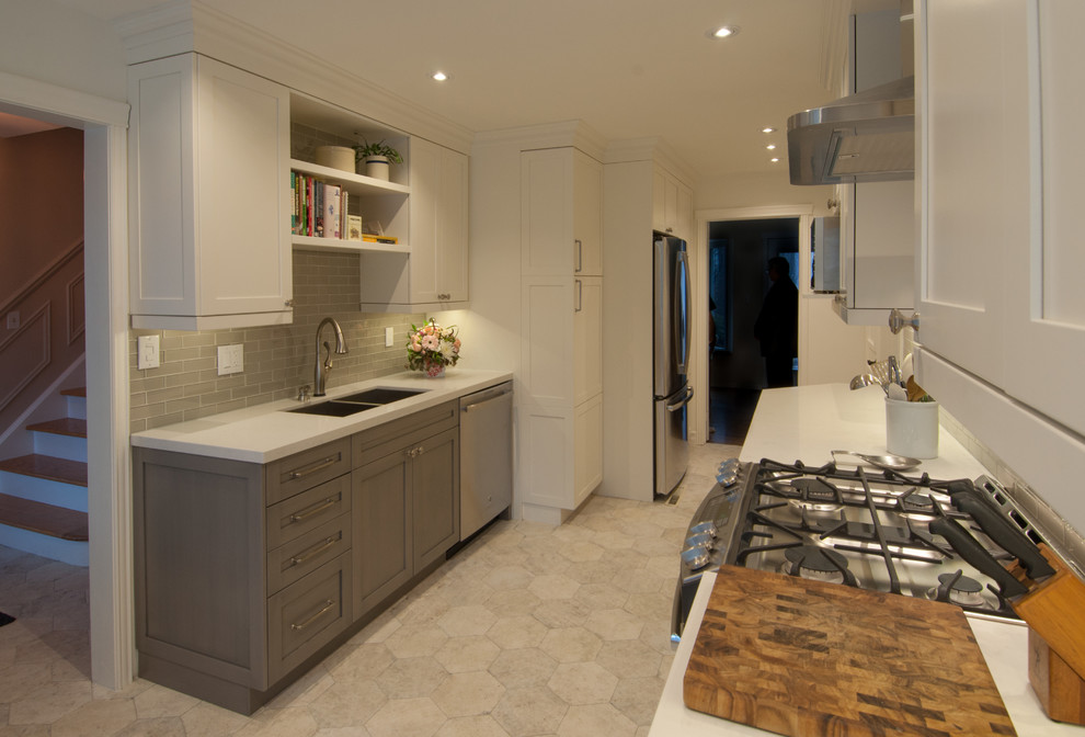 Mid-sized transitional galley ceramic tile enclosed kitchen photo in Toronto with shaker cabinets, white cabinets, quartzite countertops, gray backsplash, glass tile backsplash, stainless steel appliances and no island