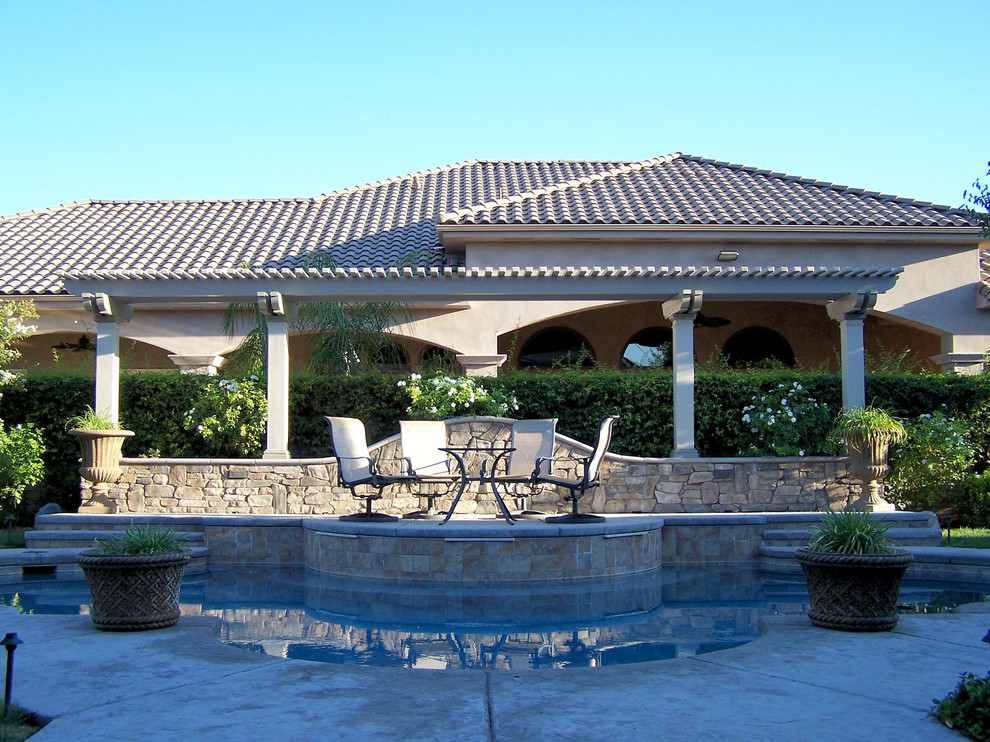 Photo of a mid-sized mediterranean backyard patio in Other with a water feature, concrete slab and a pergola.