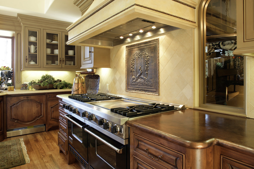 Design ideas for a mediterranean kitchen in San Francisco with copper benchtops, dark wood cabinets, beige splashback, black appliances and limestone splashback.