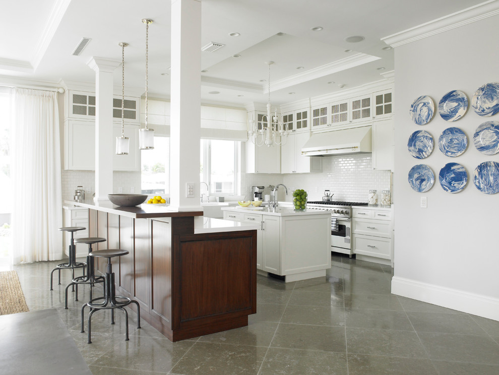 Inspiration for a large transitional l-shaped kitchen in New York with a farmhouse sink, shaker cabinets, white cabinets, stainless steel appliances, limestone floors, with island, white splashback and subway tile splashback.