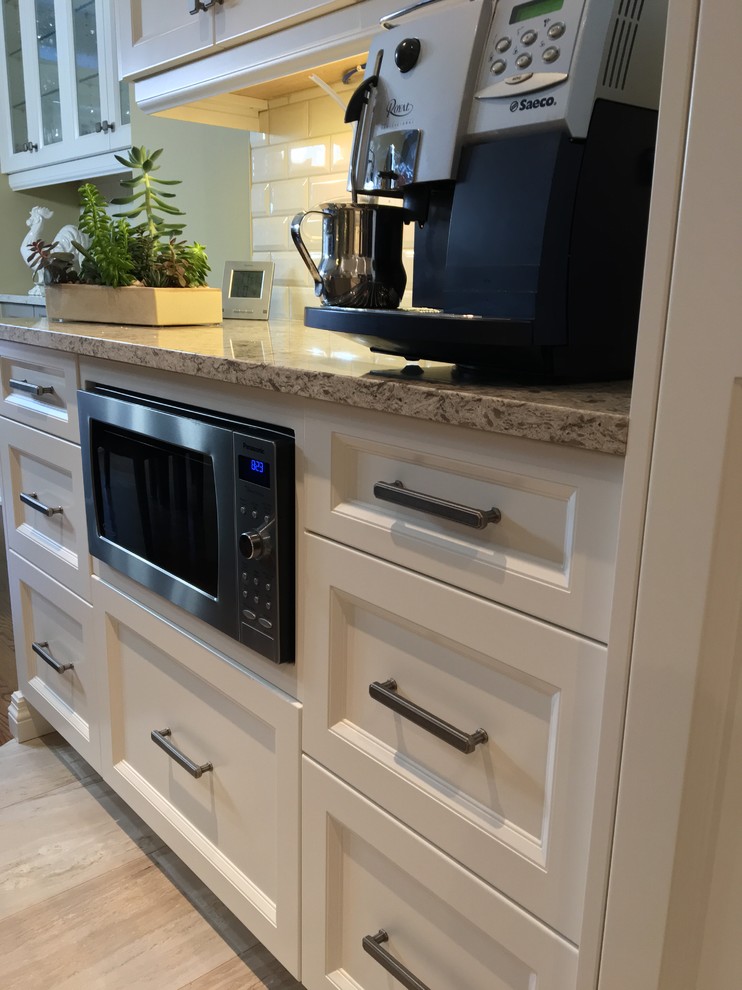 This is an example of a mid-sized contemporary l-shaped eat-in kitchen in Toronto with a double-bowl sink, flat-panel cabinets, white cabinets, quartz benchtops, white splashback, subway tile splashback, stainless steel appliances, porcelain floors, with island and grey floor.