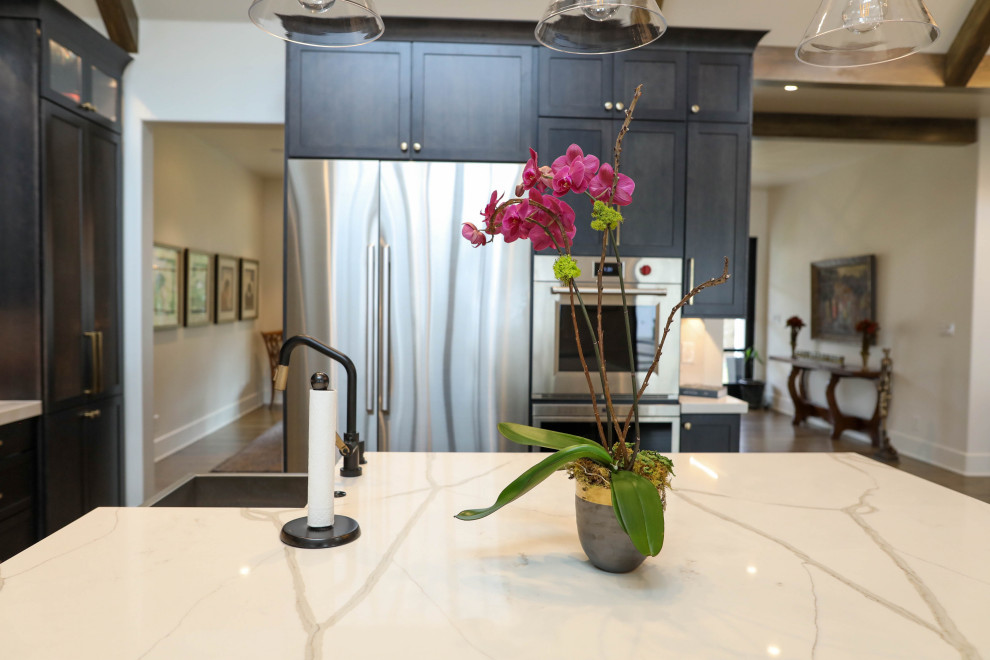 Large transitional u-shaped light wood floor open concept kitchen photo with a farmhouse sink, flat-panel cabinets, dark wood cabinets, quartz countertops, white backsplash, quartz backsplash, stainless steel appliances, an island and white countertops
