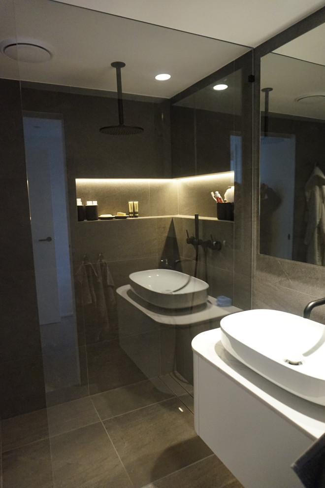 Photo of a medium sized modern bathroom in Sydney with flat-panel cabinets, white cabinets, a walk-in shower, a wall mounted toilet, grey tiles, ceramic tiles, grey walls, ceramic flooring, a console sink, engineered stone worktops, grey floors, an open shower, white worktops, a single sink and a floating vanity unit.