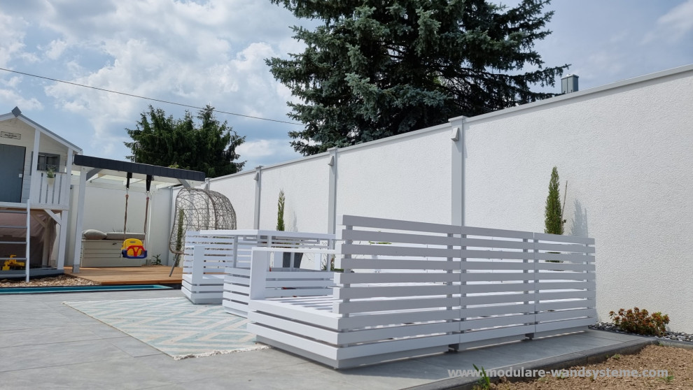 Exemple d'une grande terrasse arrière et au rez-de-chaussée tendance avec des solutions pour vis-à-vis, une extension de toiture et un garde-corps en matériaux mixtes.