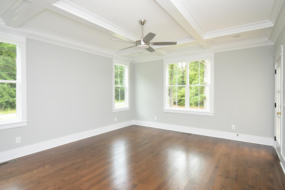 Photo of a large traditional master bedroom in Raleigh with grey walls, medium hardwood floors, brown floor and coffered.