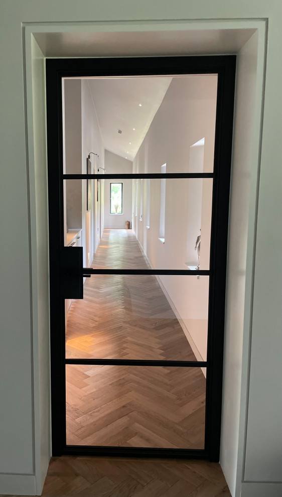 Design ideas for a mid-sized contemporary hallway in Hertfordshire with beige walls, medium hardwood floors, brown floor and vaulted.