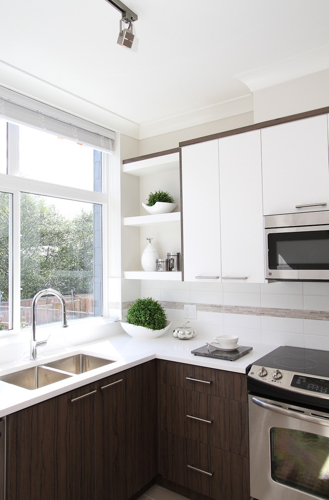 Design ideas for a mid-sized contemporary l-shaped kitchen in Vancouver with a drop-in sink, flat-panel cabinets, white cabinets, quartz benchtops, white splashback, stainless steel appliances and ceramic floors.