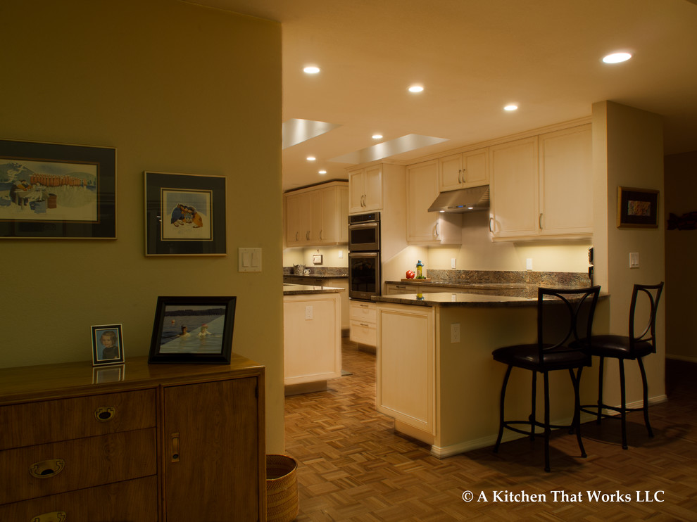 Example of a large transitional u-shaped medium tone wood floor and brown floor eat-in kitchen design in Seattle with an undermount sink, recessed-panel cabinets, white cabinets, granite countertops, stone slab backsplash, stainless steel appliances, an island, brown backsplash and brown countertops