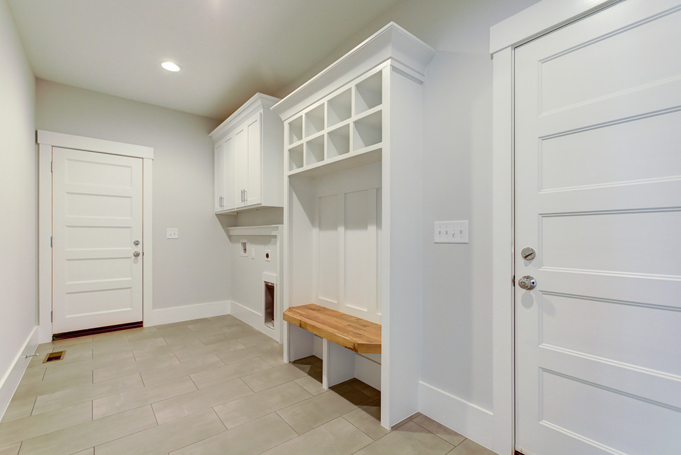 Photo of a large country galley utility room in Raleigh with shaker cabinets, white cabinets, grey walls, porcelain floors, a side-by-side washer and dryer and grey floor.