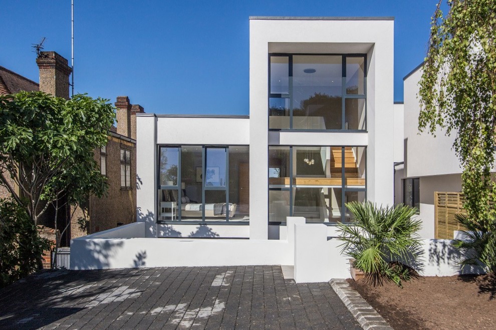 Photo of a large modern three-storey stucco white duplex exterior in London with a flat roof and a metal roof.