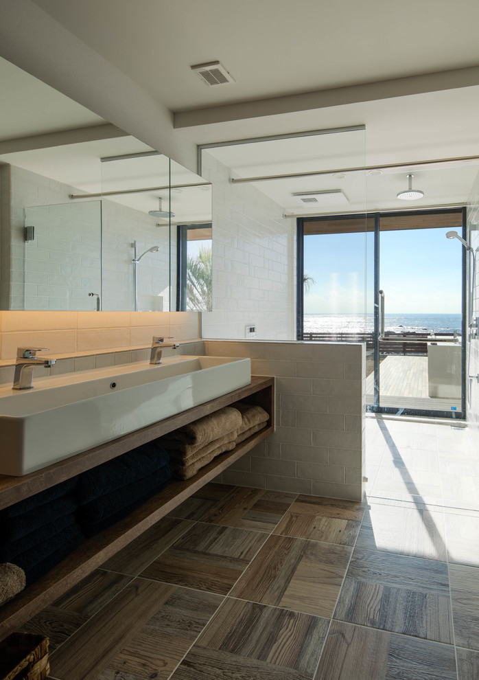 This is an example of a beach style bathroom in Other with open cabinets, brown cabinets, a freestanding tub, a double shower, white tile, porcelain tile, white walls, porcelain floors, a vessel sink, solid surface benchtops, brown floor and a hinged shower door.