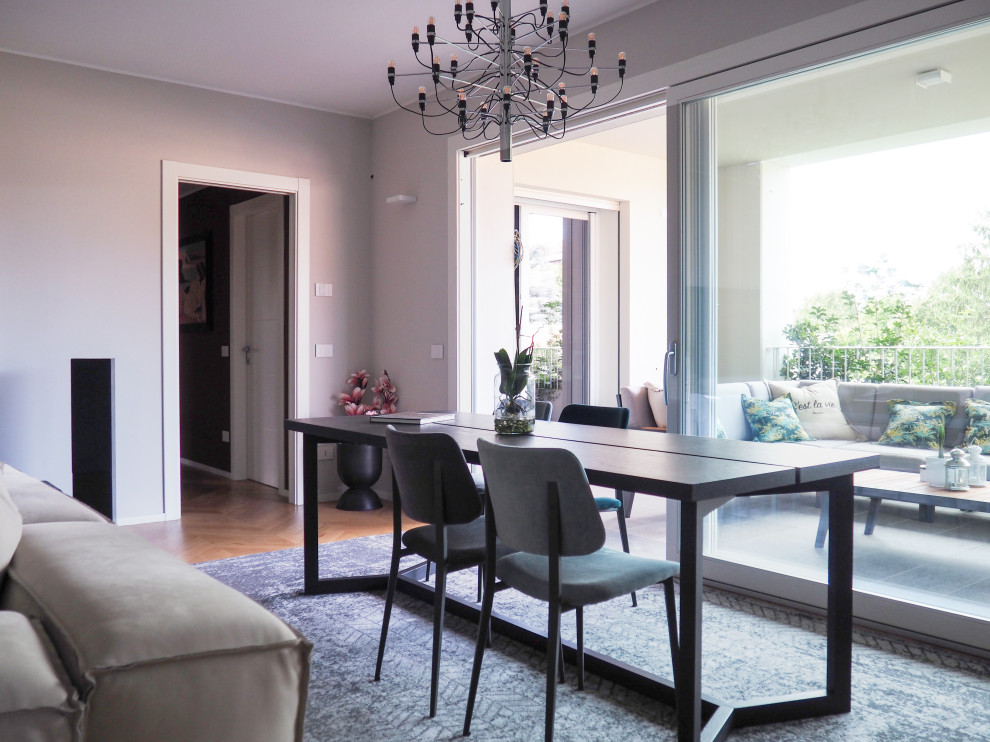 Foto di una sala da pranzo aperta verso il soggiorno contemporanea di medie dimensioni con pareti grigie e parquet chiaro