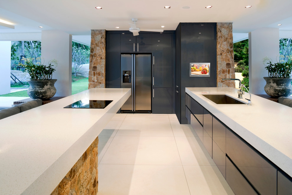 Photo of an expansive modern galley eat-in kitchen in Milwaukee with flat-panel cabinets, black cabinets, with island, an undermount sink, limestone benchtops, black splashback, stone tile splashback, stainless steel appliances and ceramic floors.