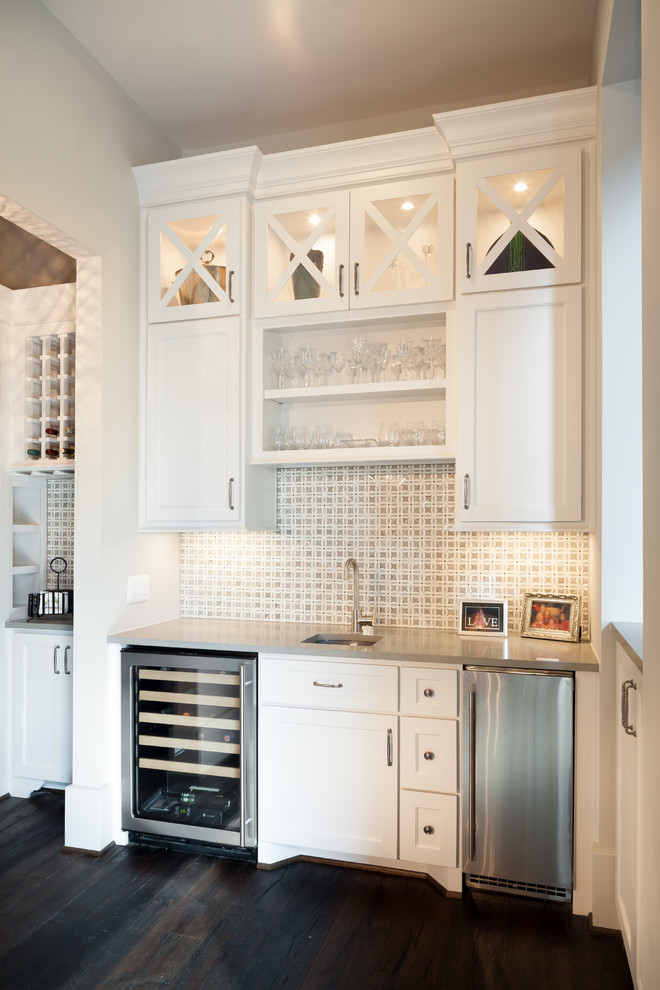 Inspiration for a transitional dark wood floor and brown floor wet bar remodel in Houston with an undermount sink, shaker cabinets, white cabinets and white backsplash