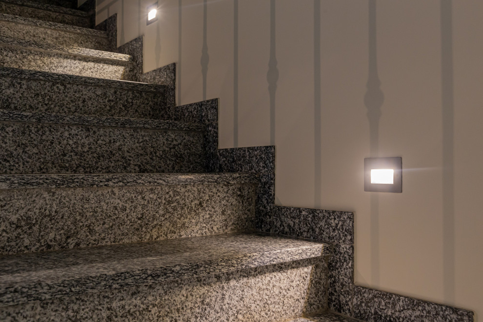 Mid-sized contemporary marble l-shaped staircase in Milan with metal risers and metal railing.