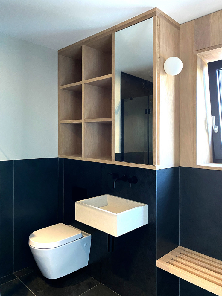 This is an example of a medium sized contemporary cream and black bathroom in Other with open cabinets, light wood cabinets, a walk-in shower, a wall mounted toilet, white walls, ceramic flooring, a wall-mounted sink, black floors, an open shower, a wall niche, a single sink and a built in vanity unit.