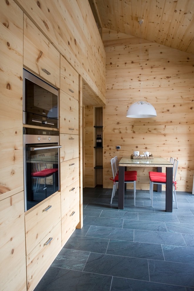This is an example of a country kitchen/dining combo in Milan with slate floors.
