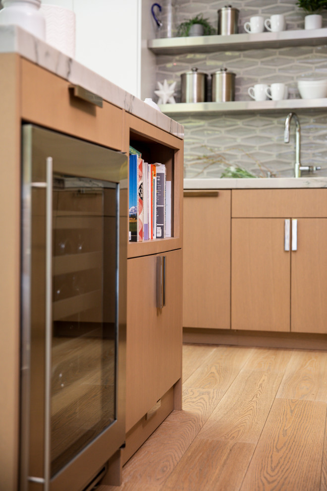 Modelo de cocina contemporánea con armarios con paneles lisos, encimera de cuarcita, electrodomésticos con paneles, suelo de madera en tonos medios y una isla