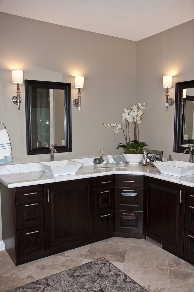 Mid-sized transitional master bathroom in Salt Lake City with a vessel sink, raised-panel cabinets, dark wood cabinets, marble benchtops, beige tile, stone tile, beige walls and travertine floors.