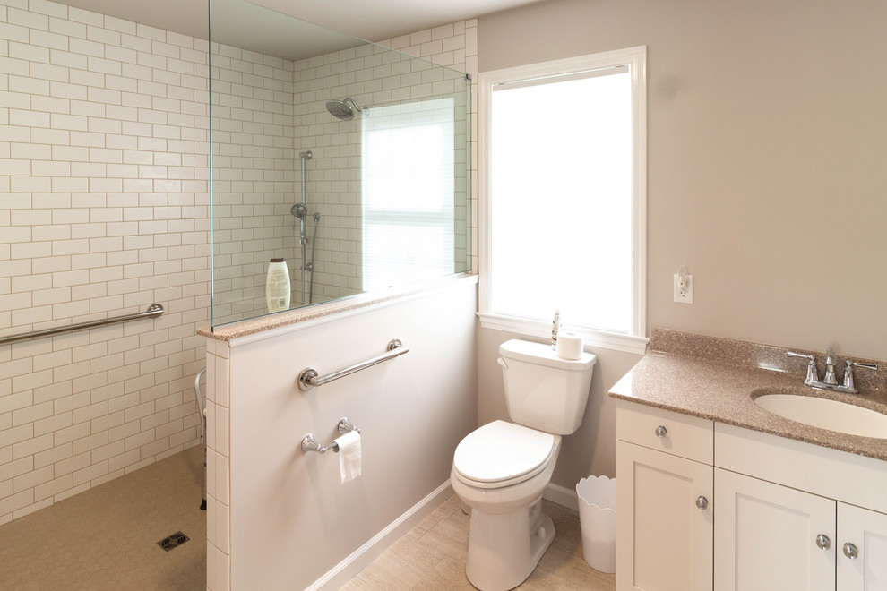 Design ideas for a mid-sized traditional master bathroom in Other with recessed-panel cabinets, white cabinets, a curbless shower, a two-piece toilet, white tile, ceramic tile, beige walls, porcelain floors, an integrated sink, solid surface benchtops, beige floor, an open shower and beige benchtops.