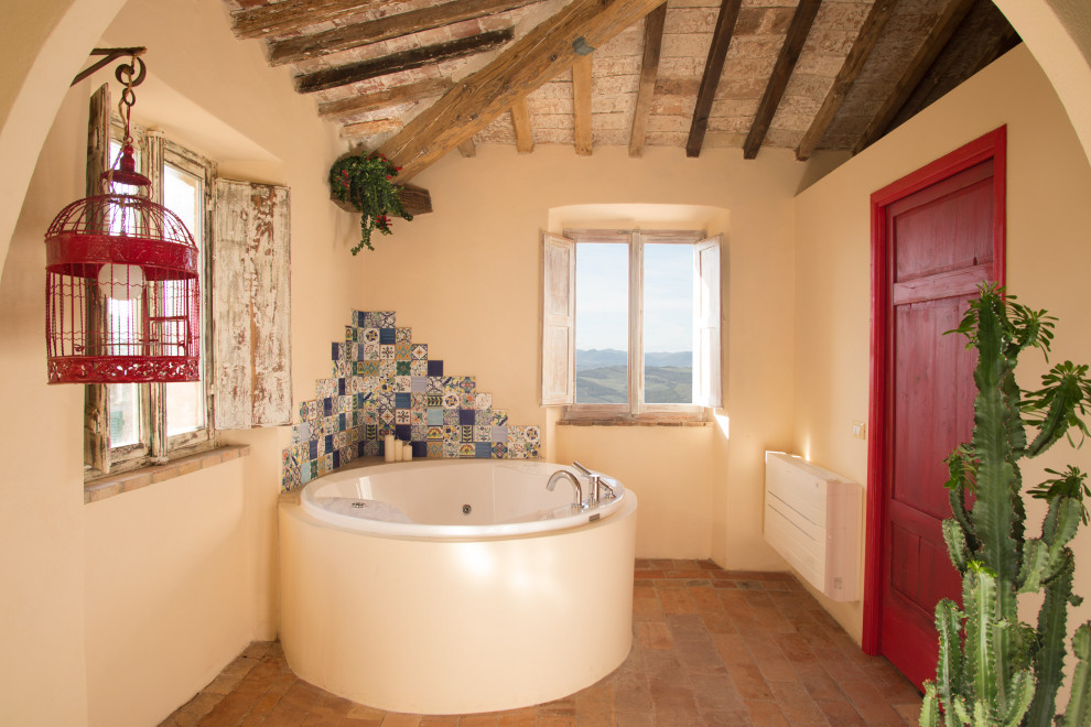 This is an example of a mid-sized mediterranean bathroom in Other with blue walls, terra-cotta floors, red floor, open cabinets, dark wood cabinets, a corner tub, an open shower, a vessel sink and wood benchtops.
