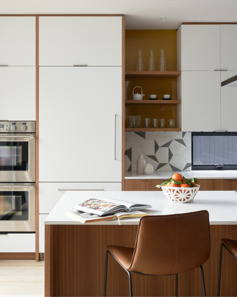 This is an example of a mid-sized scandinavian l-shaped eat-in kitchen in Seattle with flat-panel cabinets, medium wood cabinets, quartz benchtops, grey splashback, cement tile splashback, stainless steel appliances, light hardwood floors, with island, white floor and white benchtop.