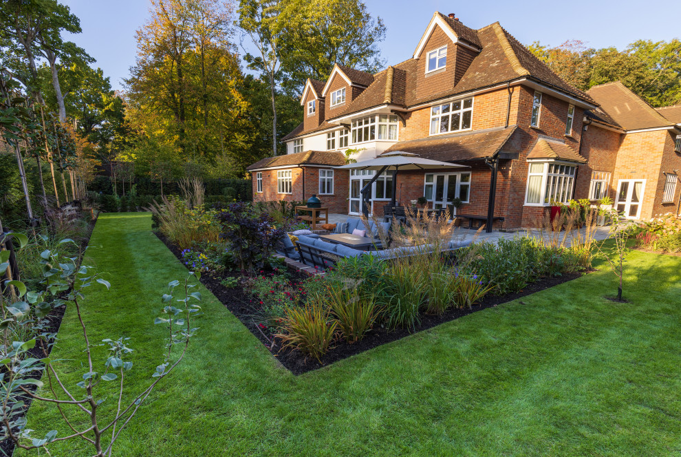 Photo of a large contemporary back formal full sun garden for summer in Buckinghamshire with a flowerbed, brick paving and a wood fence.