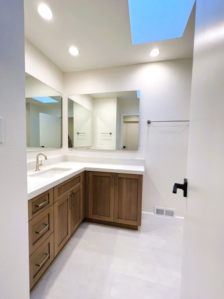 Photo of a medium sized midcentury family bathroom in San Francisco with shaker cabinets, brown cabinets, an alcove bath, a shower/bath combination, a one-piece toilet, beige tiles, porcelain tiles, white walls, porcelain flooring, a submerged sink, engineered stone worktops, beige floors, a shower curtain, white worktops, a wall niche, a single sink and a built in vanity unit.